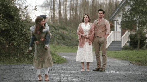 a man is carrying a child on his shoulders while a woman stands next to him