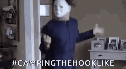 a person wearing a white mask is standing in a doorway .