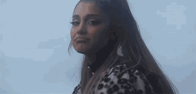 ariana grande is wearing a leopard print dress and choker while singing .