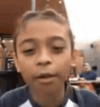 a young boy is making a funny face in front of a camera .