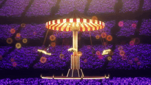 a merry go round is surrounded by purple flowers in a stadium