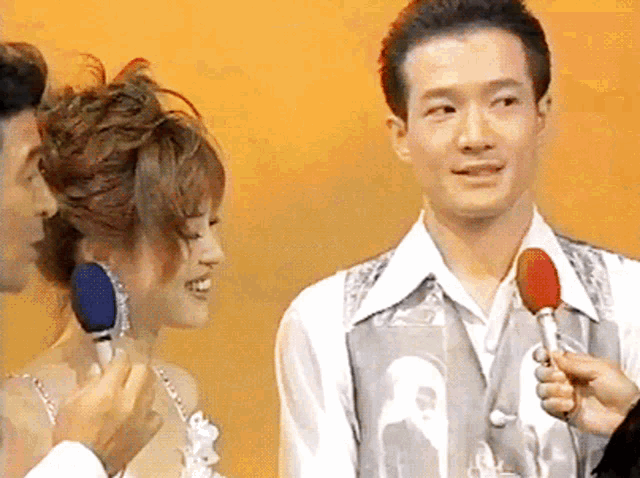 a man is holding a microphone while a woman looks on