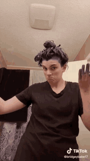 a woman in a black shirt has her hair dyed purple and is making a face
