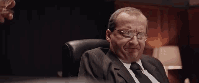 the man is wearing glasses and a suit and tie .