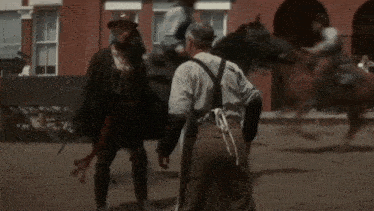 a man in a hat is pointing a gun at another man in a white apron