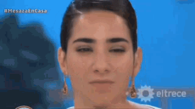 a close up of a woman wearing earrings and a bun