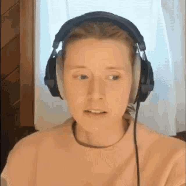 a woman is wearing headphones and looking at the camera .