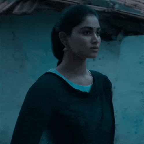 a woman in a black top stands in front of a blue building