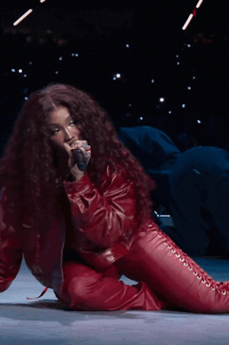 a woman with long red hair is singing into a microphone on a stage