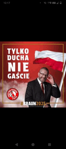 a man in a suit and tie stands in front of a polish flag