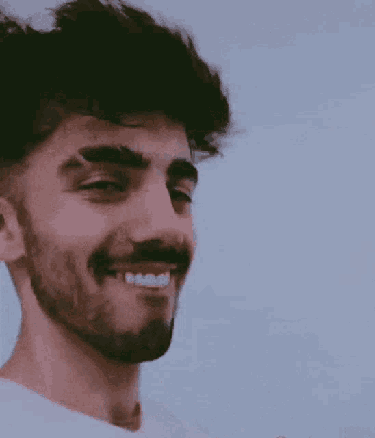 a man with a beard is smiling with his teeth visible