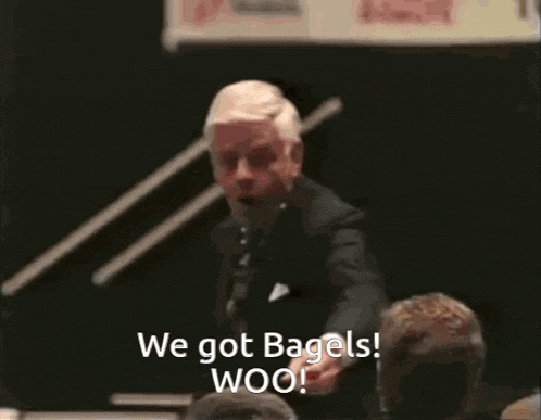 a man in a suit and tie is giving a speech and says " we got bagels woo "