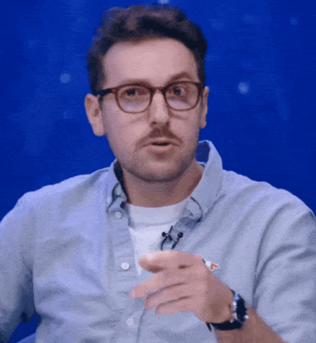 a man wearing glasses and a watch is pointing his finger