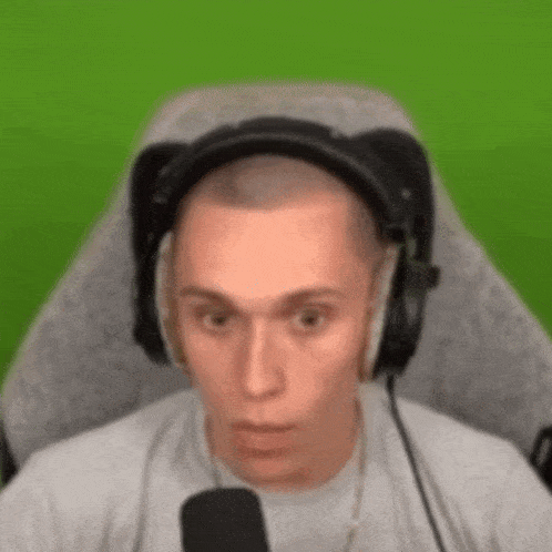 a man wearing headphones is sitting in a chair in front of a green screen .