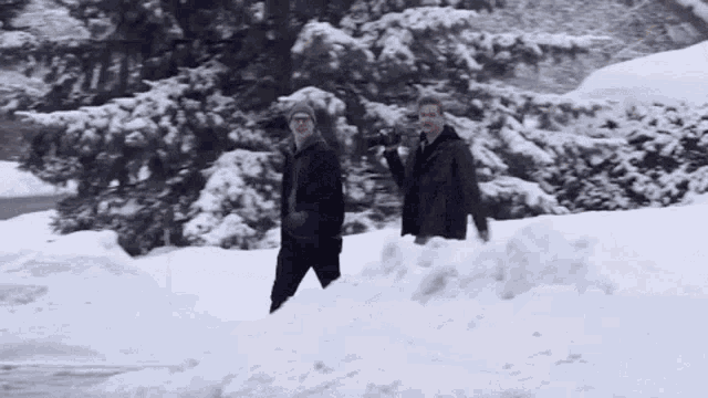 two men are walking through a pile of snow .