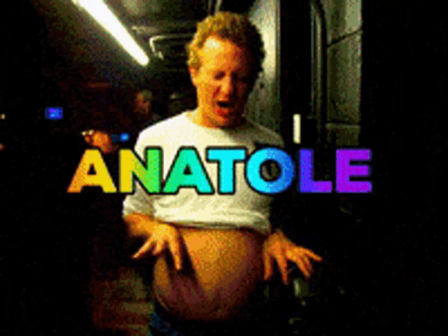 a man in a white shirt is standing in front of a sign that says anatol
