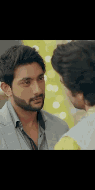 a man with a beard is looking at another man 's face in a close up .