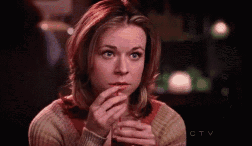 a woman is sitting at a table with a drink in her hand and looking at the camera .