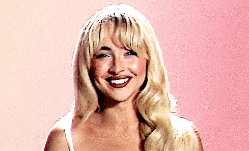 a woman with blonde hair is smiling and wearing a white tank top