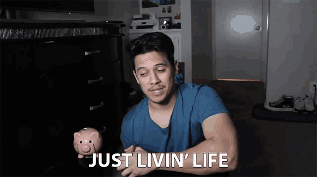 a man holding a piggy bank with the words just livin ' life above him