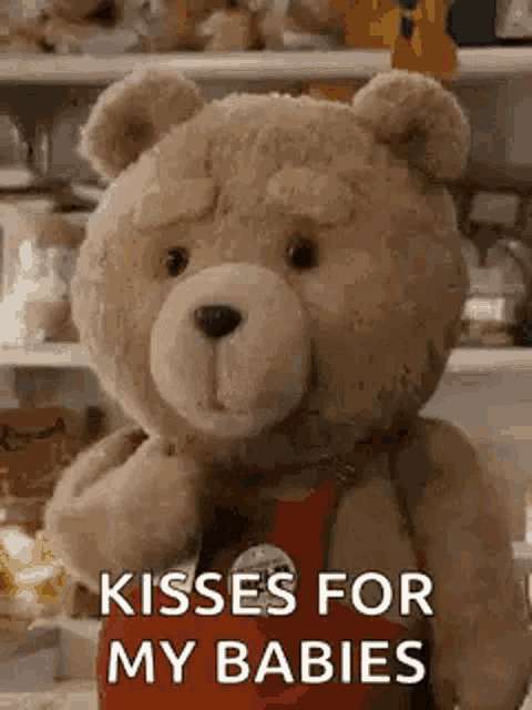 a teddy bear is holding a piece of popcorn and saying `` kisses for my babies ''