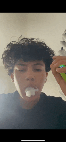 a young man with curly hair is smoking a cigarette with smoke coming out of his mouth