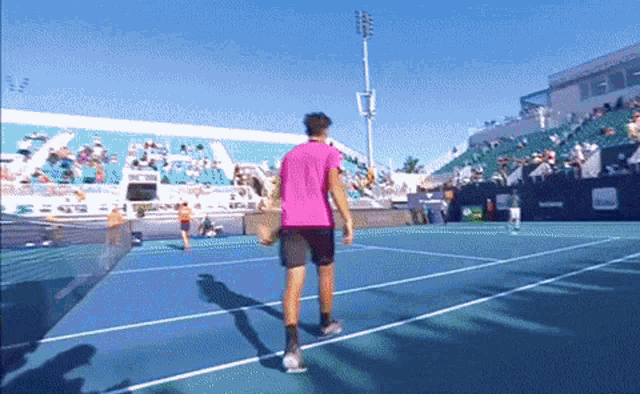 a tennis player in a pink shirt is walking on a court