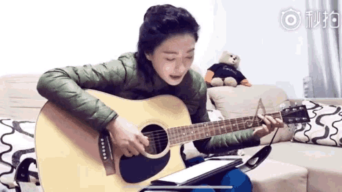 a woman in a green jacket is playing an acoustic guitar in front of a teddy bear wearing a calvin klein shirt