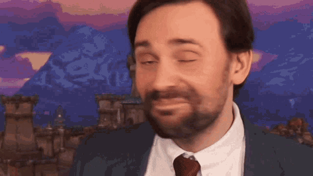 a man with a beard is wearing a suit and tie