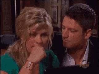 a man and a woman are sitting next to each other looking at a laptop screen .