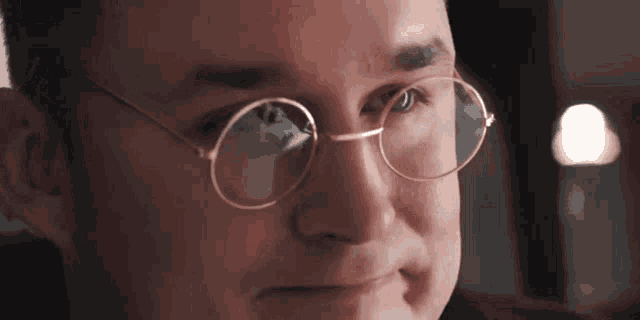 a close up of a man wearing glasses looking at something