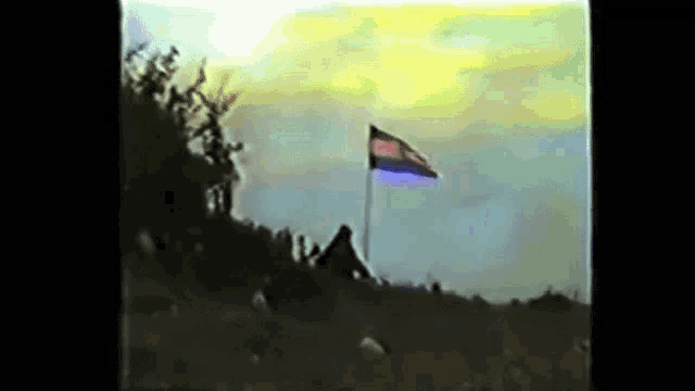 a rainbow flag is flying in the wind in front of a crowd of people