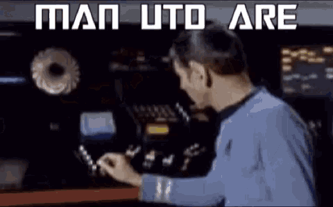 a man in a blue shirt is playing a video game with the words man utd are above him .