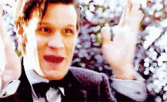 a man in a suit and bow tie is waving his hand in front of flowers .