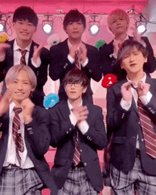 a group of young men in school uniforms and ties are standing next to each other .