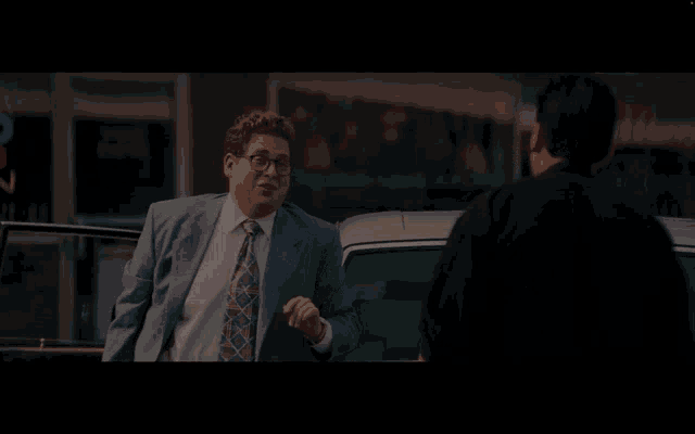 a man in a suit and tie shakes another man 's hand
