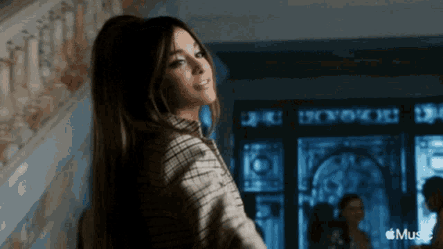 a woman in a plaid shirt is standing in front of a door that says ' music ' on it
