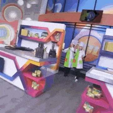 two chefs are standing in front of a colorful kitchen .