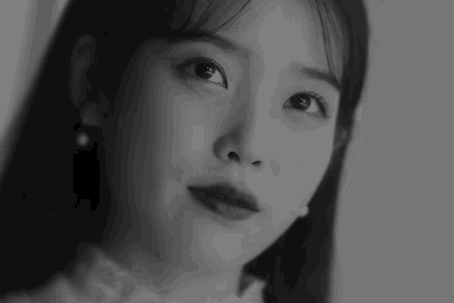 a black and white photo of a woman 's face with a pearl earring