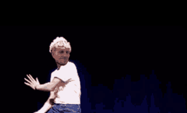 a man wearing a white shirt that says vote for elvis is dancing on a stage