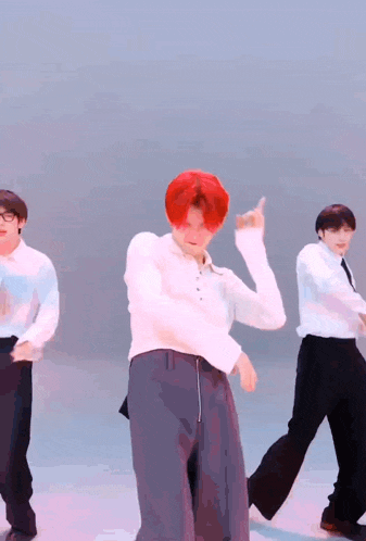 a man with red hair is dancing with other men