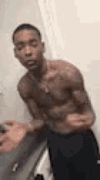 a shirtless man is standing in a bathroom with his hands on his hips .