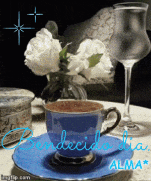 a cup of coffee sits on a saucer next to a vase of flowers and a glass of water