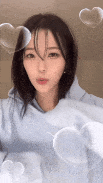 a woman in a light blue hoodie surrounded by hearts