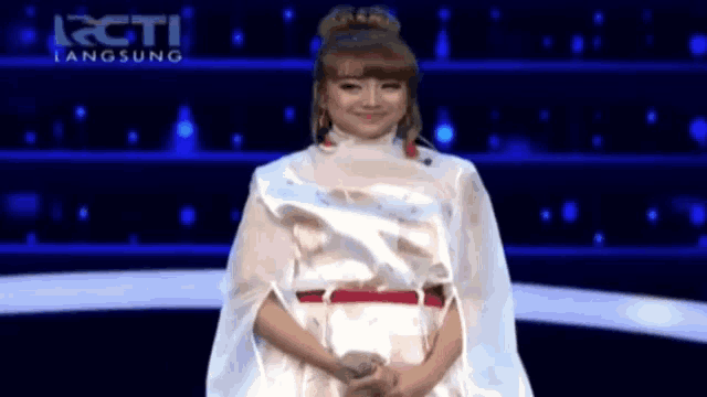 a woman in a white dress stands in front of a rcti advertisement