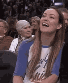 a woman is sitting in a crowd of people laughing .