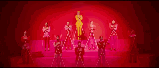 a group of people are standing next to each other on a stage holding sticks .