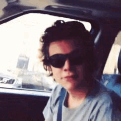 a man wearing sunglasses is driving a car