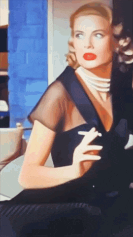 a woman in a black dress is holding a cigarette