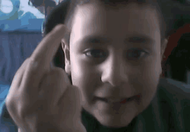 a young boy is giving the middle finger and smiling .
